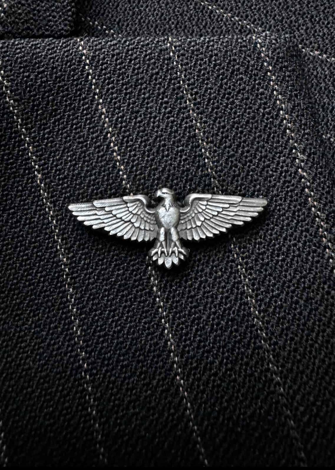 The American Eagle pin in antique nickel, worn on a dark pinstripe lapel