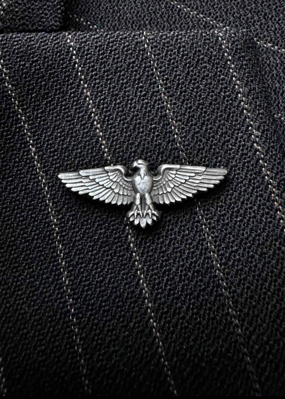 The American Eagle pin in antique nickel, worn on a dark pinstripe lapel